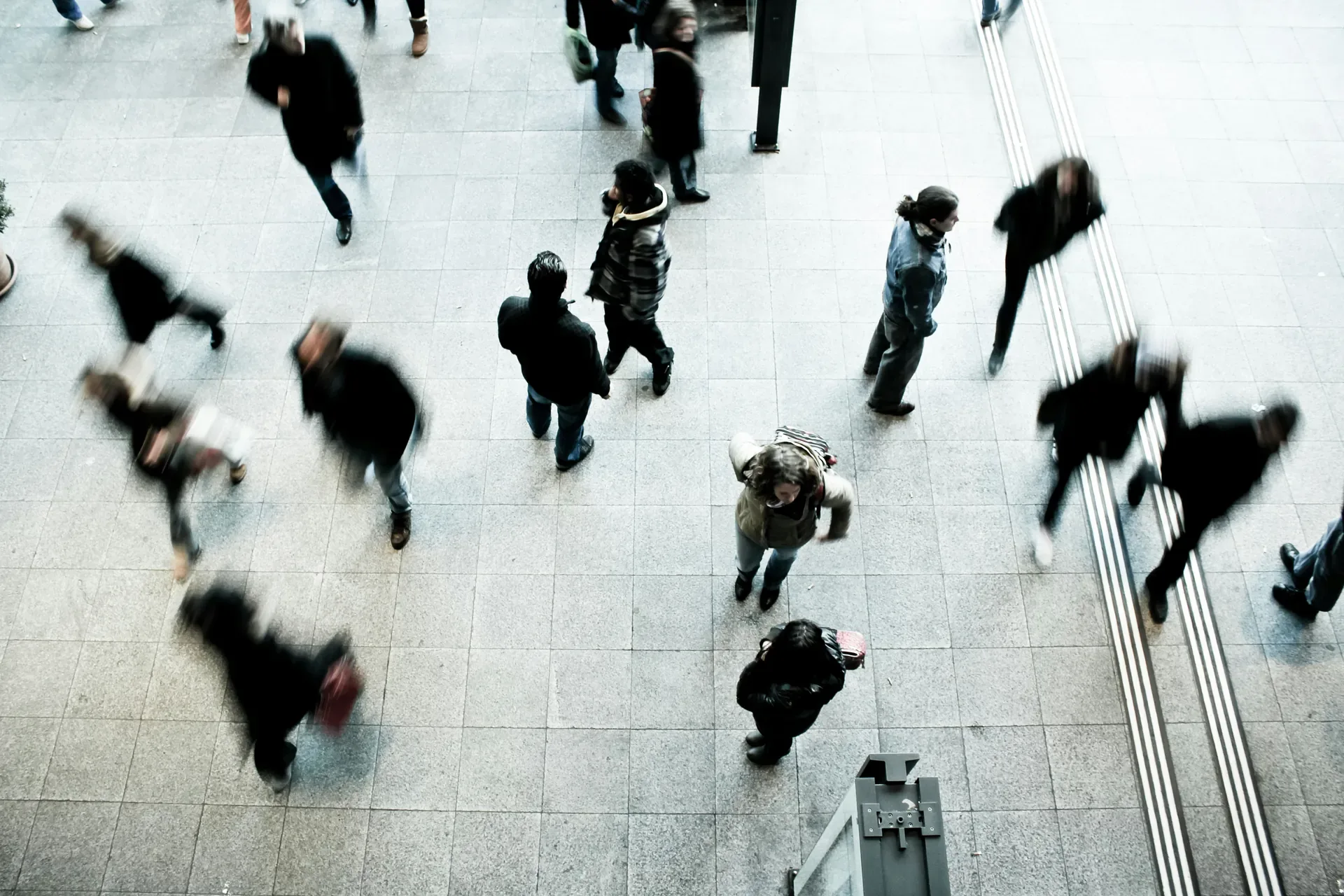 People walking through a busy indoor public space while a few stand still